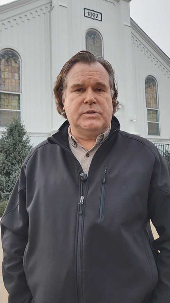 Chicago area home inspector Jamie Dunsing talks about how great ScribeWare inspection report software is for his team. He wears a black jacket in front of a white church with 1867 over the door.